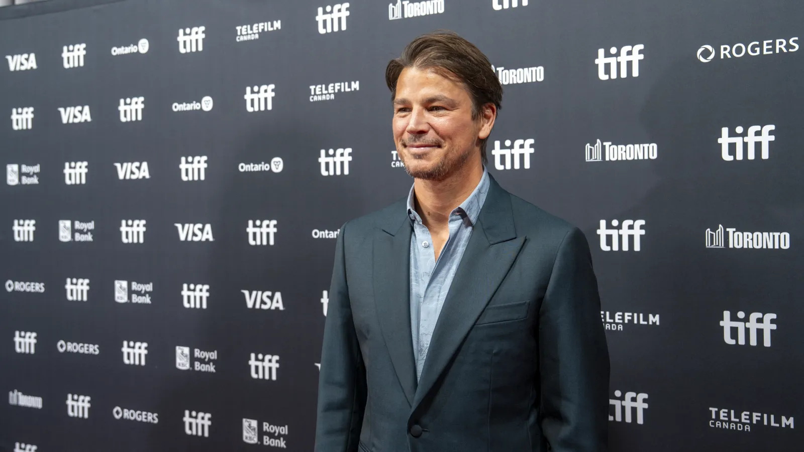 Josh Hartnett in a dark suit and open-collared shirt on the red carpet at the Toronto International Film Festival