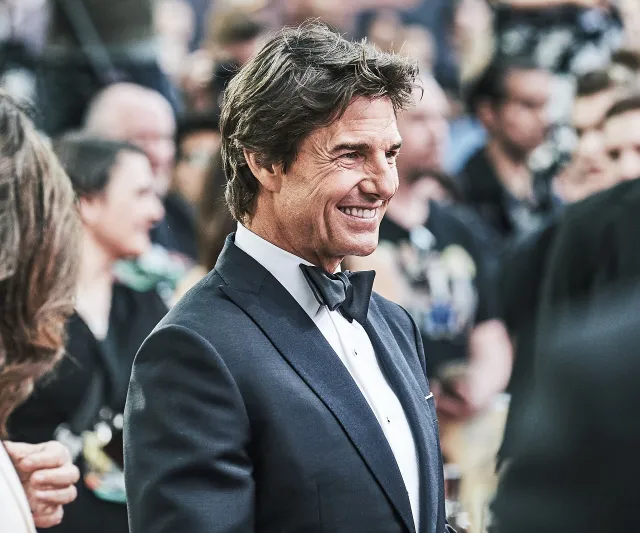 Tom Cruise smiling in a tuxedo at a film premiere