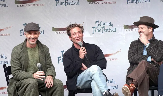 Jeremy Strong and Jeremy Allen White laughing on a festival panel stage next to director Scott Cooper